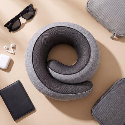 The travel pillow laid flat with sunglasses, earphones, a passport wallet and travel pouches