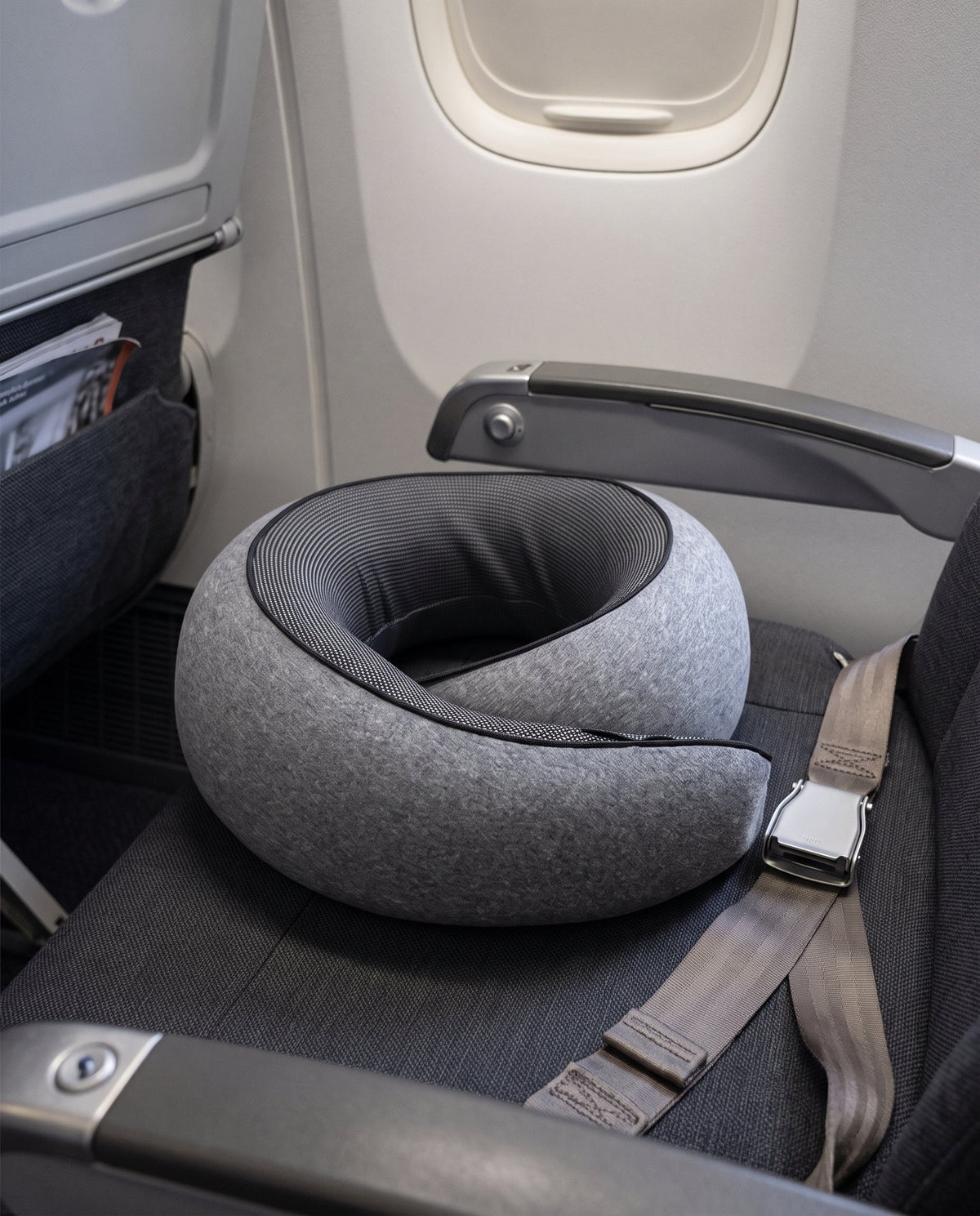 The travel pillow resting on an aeroplane seat beside the window