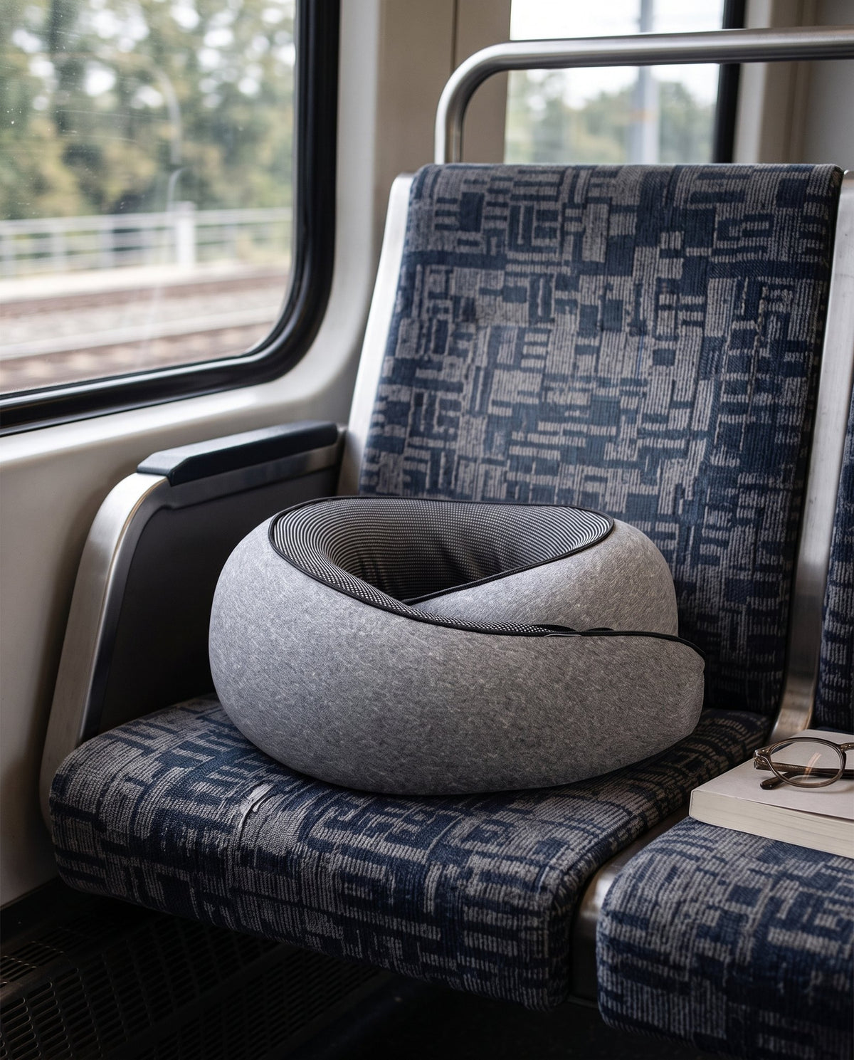 The travel pillow resting on a train seat beside the window