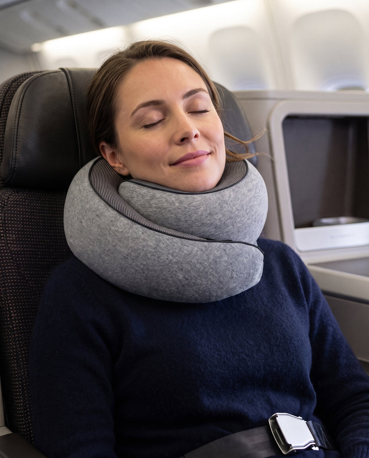 A traveller resting with the KABINBAG travel pillow around their neck on a flight